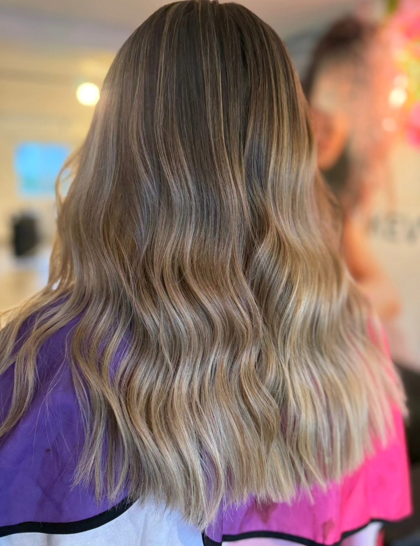 A Luscious stylist finishing a client's blowdry at the mirror.